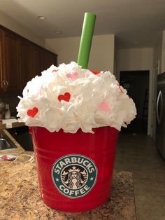 a starbucks drink with whipped cream and sprinkles in a red cup on a kitchen counter