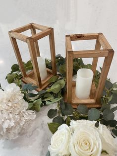 two wooden lanterns with white flowers and greenery