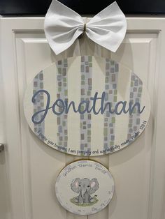 a wooden sign that says jonathan with an elephant and a white bow hanging on the front door