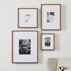 three framed photographs hang on the wall above a chair in front of a white couch