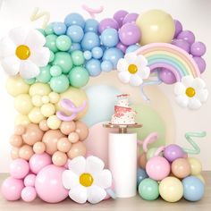 a birthday cake surrounded by balloons and flowers