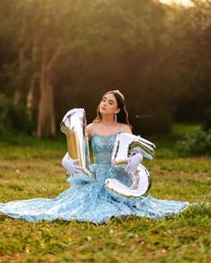 a woman sitting in the grass with her number twenty five balloons and wearing white gloves