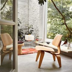 a living room filled with furniture next to a large glass window covered in greenery