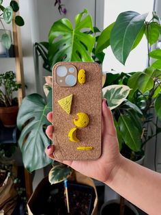 a person holding up a phone case with some yellow decorations on the front and back