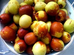 a white bowl filled with lots of yellow and red apples