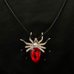 Please read descriptions thoroughly for sizes and materials.  This is an unusual and fun gold metal pendant featuring a gold metal tarantula spider, covered in sparkling faceted white colored gems, with a large white gem on the body, and a huge red gem making up the remainder of the body. It is hung from a black faux leather woven waxed cord that is 19 1/2" long, with gold chain and a gold lobster claw clasp. * Also available on an 18" 20" 24" or 30"  gold stainless steel snake chain.  Make sure Red Novelty Jewelry For Halloween, Novelty Gold Pendant Jewelry, Gold Novelty Jewelry For Party, Gold Necklace For Halloween Party, Halloween Party Pendant Jewelry, Red Novelty Jewelry With Charms, Novelty Red Charms Jewelry, Novelty Red Jewelry With Charms, Tarantula Spider