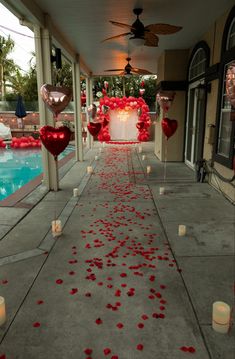 an outdoor walkway with candles and rose petals on the ground next to a swimming pool