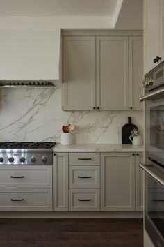 a kitchen with white cabinets and marble counter tops