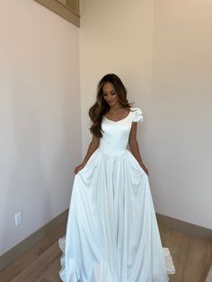 a woman in a white dress standing on a wooden floor with her hands on her hips