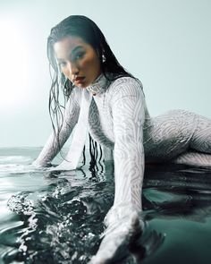 a woman in white bodysuit laying on the water with her hands behind her head