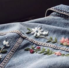 an embroidered denim jacket with flowers on it