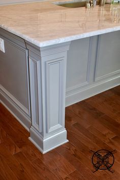 a kitchen island with marble counter tops and wooden floors