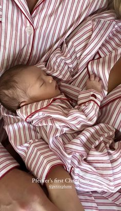 a woman holding a baby wrapped in a red and white striped blanket