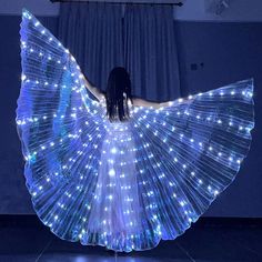 a woman in a white dress with blue lights on her body and wings spread out