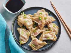 some dumplings are sitting on a plate with chopsticks next to it and a cup of coffee