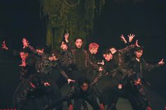 a group of young men standing on top of each other in front of a stage