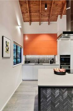 an orange and white kitchen with wooden ceiling