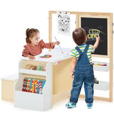 two children are playing with their toys in the playroom, while one child is writing on a chalkboard