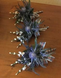 three dried flowers are sitting on a wooden table next to a vase with white and blue flowers