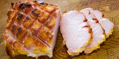 two slices of ham sitting on top of a wooden cutting board