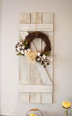 a white door with a wreath hanging on it and some flowers in front of it