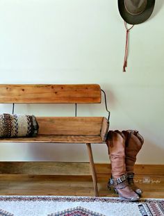 a wooden bench sitting next to a hat on top of a rug