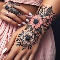 a woman's arm with flowers and feathers on it, while holding her hand