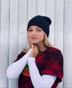 a woman wearing a black beanie is posing for the camera with her hand on her face