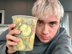 a man holding up a cup with cucumbers on it in front of his face