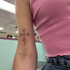 a woman's arm with a cross tattoo on the left side of her right arm