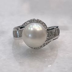 a pearl and diamond ring on a white surface