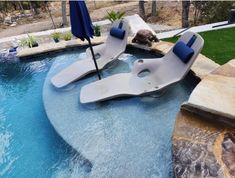 an outdoor swimming pool with lounge chairs and umbrellas in the middle, surrounded by grass