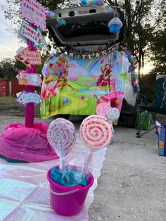 a pink bucket filled with lollipops sitting on top of a table next to a sign