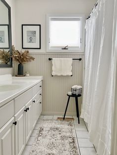 a bathroom with white cabinets and a rug on the floor in front of a window