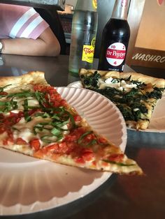 two slices of pizza sitting on top of paper plates