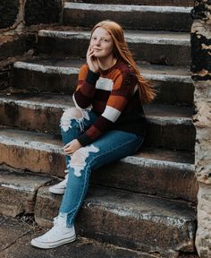 a woman sitting on some steps with her hand in her mouth and looking at the camera