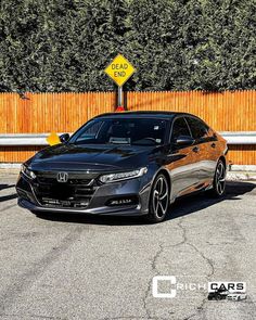 a black car is parked in front of a wooden fence and yellow sign that says high cars