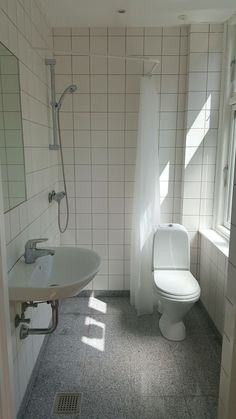 a white toilet sitting next to a sink in a bathroom on top of a tiled floor