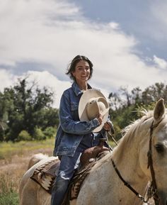 a woman riding on the back of a brown and white horse in a grassy field