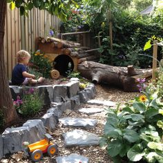 a little boy playing in his garden with toys and rocks on the ground near a tree