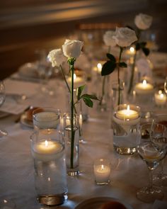 Simple single white roses and candles wedding table decor Single Stem Table Decor Wedding, Single Rose Centerpiece Simple, Minimalist White Rose Centerpiece, Single Rose Table Centerpiece, Simple Rose Table Centerpieces, Tea Light Candles Wedding Centerpieces, White Flower Table Setting, Single Roses Wedding Table, Single Rose In Vase Wedding