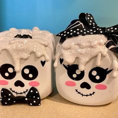 two white ceramic pots with black and white designs on them, one is wearing a bow tie