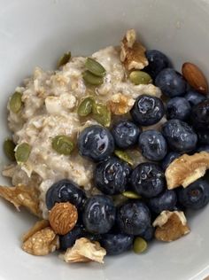 a bowl filled with oatmeal and blueberries next to some almonds