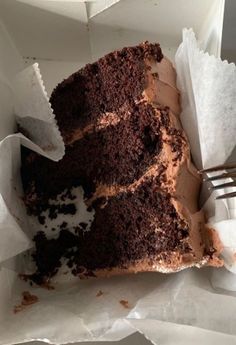 a piece of chocolate cake sitting on top of white paper with a fork in it