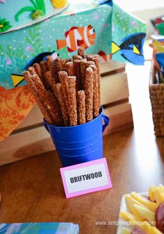 a blue bucket filled with crackers sitting on top of a table next to other snacks