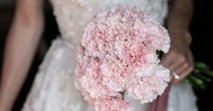 a bride holding a bouquet of pink carnations