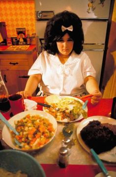 a woman sitting at a table with plates of food