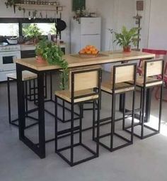 a kitchen with an island table surrounded by chairs and potted plants on the counter