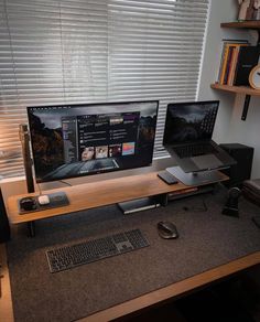 a computer desk with two monitors, keyboard and mouse on it in front of a window