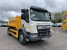 a yellow and white truck parked in a parking lot